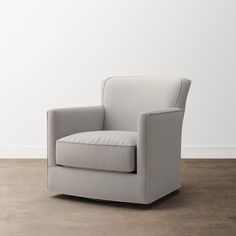 a gray chair sitting on top of a hard wood floor next to a white wall