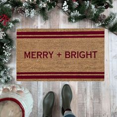 someone standing in front of a door mat that says merry and bright