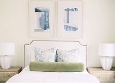 two framed pictures hang above a bed with white linens and green pillows on it