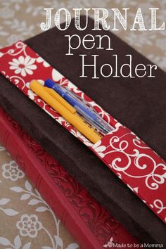 the journal pen holder is made with fabric and has two pens in it, sitting on top of each other