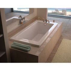 a bathroom with a large jacuzzi tub next to a window overlooking the beach