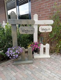 a wooden sign sitting on the side of a brick building next to flowers and potted plants