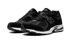 the new balance 990 running shoe is black and white with grey accents on the upper part