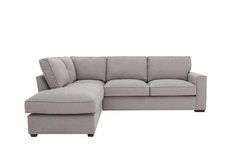 a grey sectional couch with pillows on it's back and foot rest in the middle