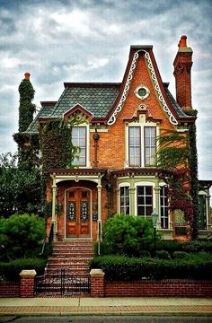 an old brick house with ivy growing on it's roof and stairs leading up to the front door