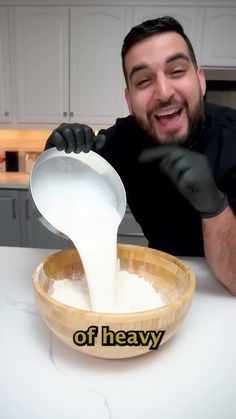 a man pouring milk into a wooden bowl on top of a white kitchen countertop