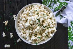 a bowl filled with popcorn sitting on top of a table next to green sprinkles