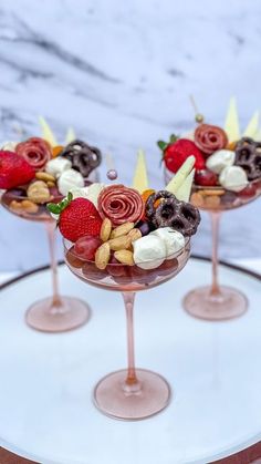 two glasses filled with fruit and nuts on top of a plate