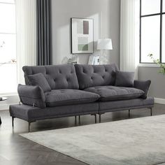 a living room with a gray couch and white rug on the hardwood floor next to a large window