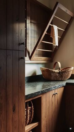 a basket is sitting on the counter in front of an open cabinet and stair case