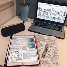 an open laptop computer sitting on top of a desk next to a notebook and pen