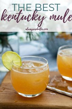 two glasses filled with drinks sitting on top of a wooden cutting board