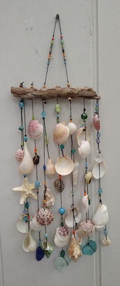 a wall hanging made out of seashells on a wooden stick with beads and shells attached to it