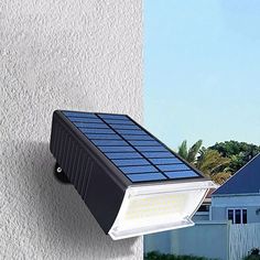 a solar powered light mounted on the side of a building next to a white house