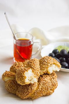 several bagels on a plate next to a bowl of blueberries and a cup of tea