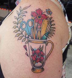 a woman's shoulder with scissors and flowers in a vase