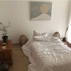 a white bed sitting in a bedroom next to a painting on the wall above it