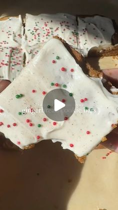 a person is holding up a doughnut with white frosting and sprinkles