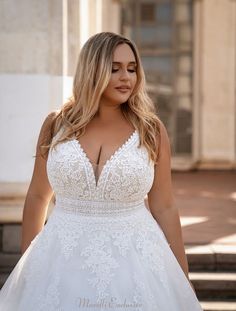 a woman in a white wedding dress standing on the steps with her hands behind her back