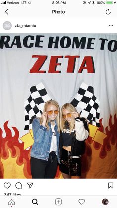 two women standing next to each other in front of a photo booth with the words race home to zeta on it