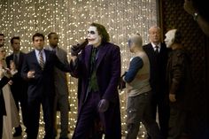 a group of people standing around each other in front of a man dressed as the joker