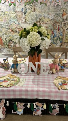 a table topped with bunny figurines sitting next to a vase filled with flowers