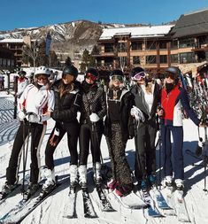 a group of people standing next to each other on top of a snow covered slope