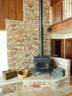 a wood burning stove sitting in the middle of a living room next to a stair case