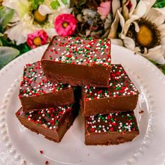 several pieces of chocolate fudge cake on a white plate with flowers in the background