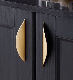 a black cabinet with two brass handles on the front and back doors, along with a marble counter top