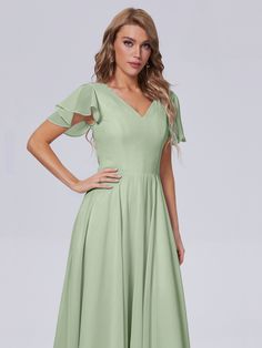 a woman wearing a green dress with short sleeves and pleaed skirt, posing for the camera