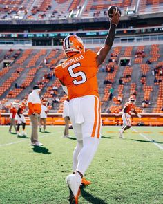 a football player in an orange and white uniform is throwing a ball on the field