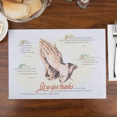 a place mat with a praying hands on it next to silverware and other food