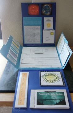 an open blue folder with pictures and other items on it's side, sitting on a table