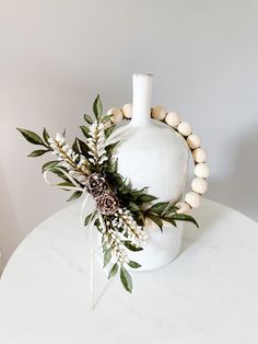 a white vase sitting on top of a table next to a wooden beaded bracelet