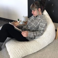 a woman sitting on a bean bag chair reading a book