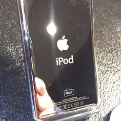 a hand holding an apple ipod in a clear plastic case on a black countertop