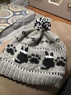 a knitted hat with black and white skulls on it sitting on a couch in front of a fireplace