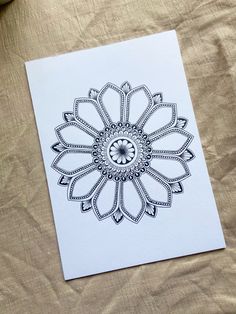 a white card with a black and white flower design on the front, sitting on a bed