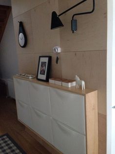 a white cabinet sitting in the corner of a room next to a wall mounted clock