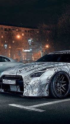 two sports cars parked next to each other on the street at night with buildings in the background