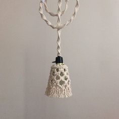 a white bell hanging from a rope on a wall