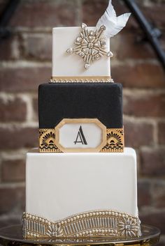 a three tiered wedding cake with black, white and gold accents