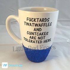 a blue and white coffee cup with words on the side that says fuctards, twaffles, and cuntcakes are not tolerated here