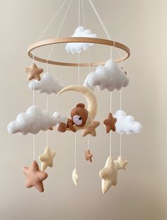 a teddy bear is sitting on the moon and stars mobile hanging from it's ceiling