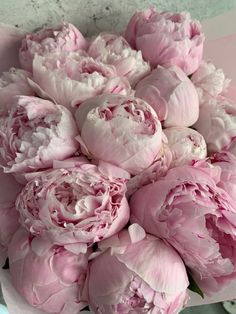 a bouquet of pink peonies sitting on top of a table