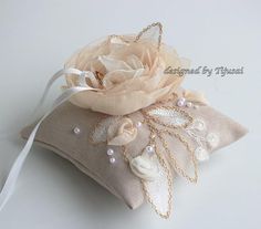 a white flower on top of a pillow covered in pearls and lace, sitting on a table