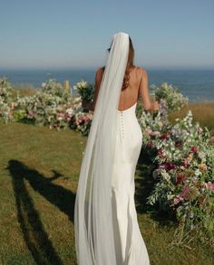 the back of a bride's wedding dress, with her veil blowing in the wind