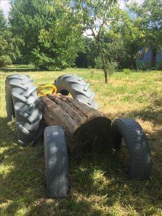 two large tires sitting on top of a wooden log in the middle of a field