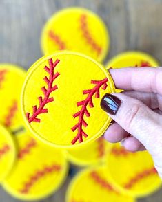 a hand holding up a yellow and red baseball patch